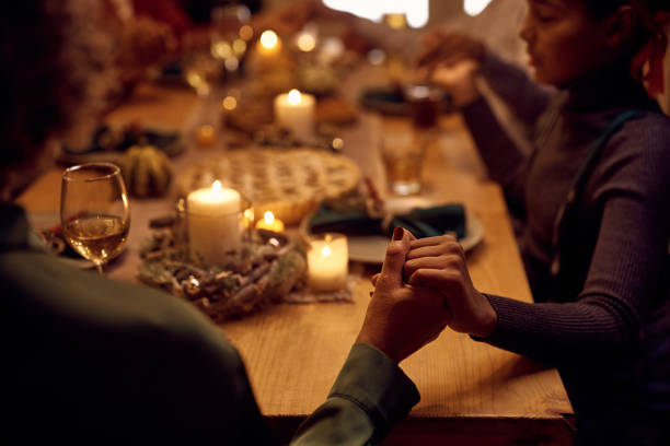 感謝祭の食事中に優雅さを言いながら手をつないでいる黒人家族のクローズアップ。 - praying saying grace dinner meal ストックフォトと画像