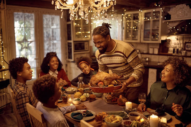 istock Happy African American man serving stuffed turkey while having dinner with his extended family in dining room on Thanksgiving. 1434915702
