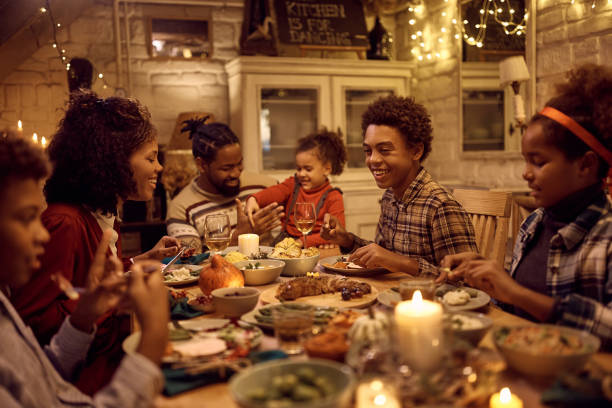 szczęśliwe czarne dziecko cieszące się rodzinnym obiadem na święto dziękczynienia przy stole jadalnym. - dining table child grandparent grandchild zdjęcia i obrazy z banku zdjęć