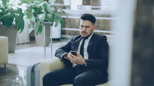 istock Bearded concentrated businessman using smartphone sit on armchair inside luxury hotel after arrivel to business meeting 1434917421