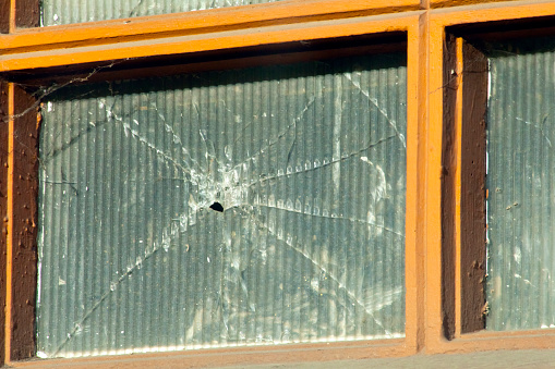 Close up view of broken window, broken glass, wooden window frame.