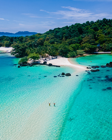 Koh Kham Trat Thailand, aerial view of the tropical island near Koh Mak Thailand. white sandy beach with palm trees and big black boulder stones in the ocean view from drone