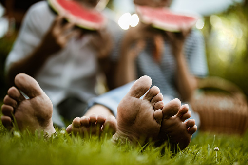 Close up of unrecognizable senior couple resting their feet on grass during picnic in nature.