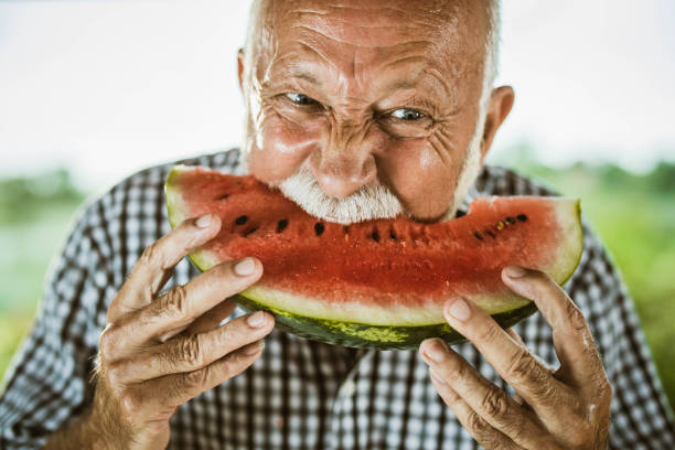 istock Mature man biting fresh watermelon outdoors. 1434923559