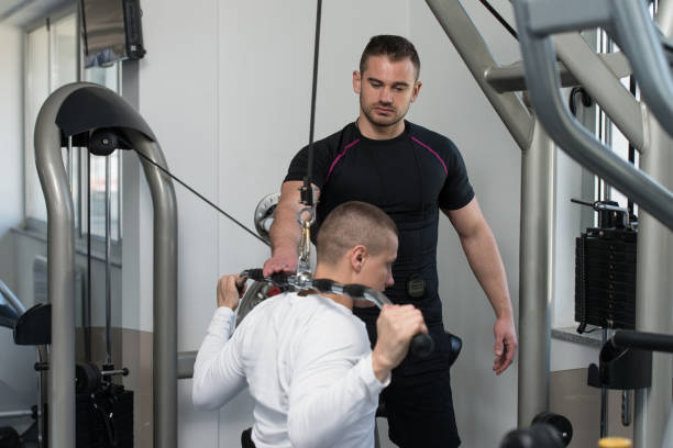 istock Personal Trainer Helping Client In Gym 1434923796