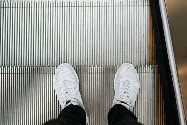 istock Man standing on the escalator. Top view, close-up, selective focus on shoes 1434923897