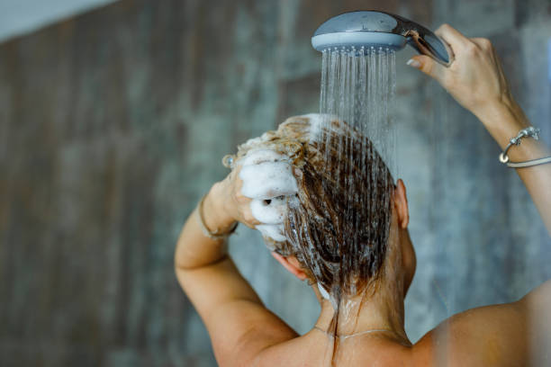 Washing hair with shampoo! Back view of a woman washing her hair with a shampoo in bathroom. Copy space. washing hair stock pictures, royalty-free photos & images