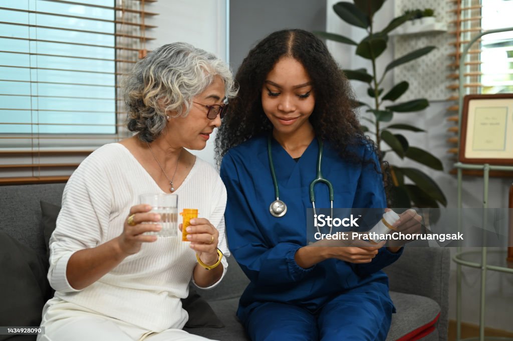 Practitioner nurse explaining medicine dosage to senior patient. Elderly healthcare and Home health care service concept. Home Caregiver Stock Photo