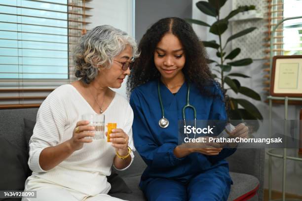 Practitioner Nurse Explaining Medicine Dosage To Senior Patient Elderly Healthcare And Home Health Care Service Concept Stock Photo - Download Image Now