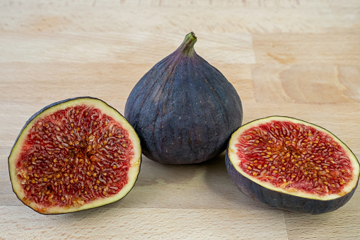 Still life with ripe sliced and whole fresh figs as healthy food for holidays. Pastel blue background. Copy space. Flat lay. Overhead view.