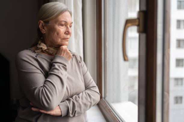 istock Lonely Senior Woman Looking Through The Window 1434933351