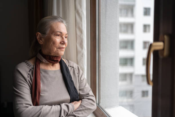 istock Lonely Senior Woman Looking Through The Window 1434933383