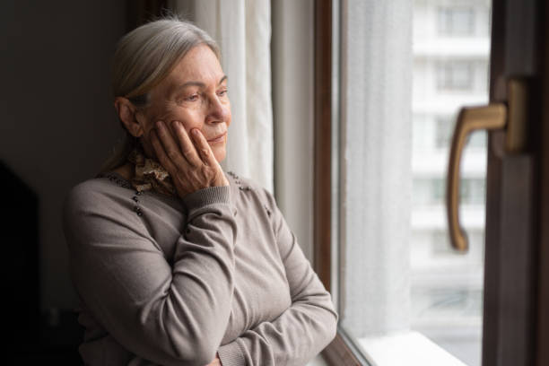 istock Lonely Senior Woman Looking Through The Window 1434933385