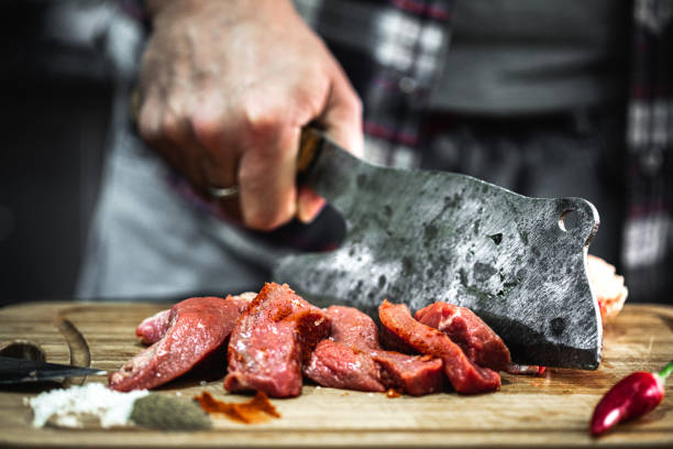 istock Man chopping meat with a butcher knife in the kitchen 1434934011