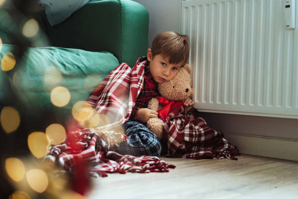 istock cute little boy wrapped id plaid sitting by heater 1434937465