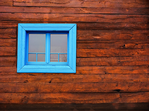 wooden farmhouse wall and a blue framed window, close up front textured view
