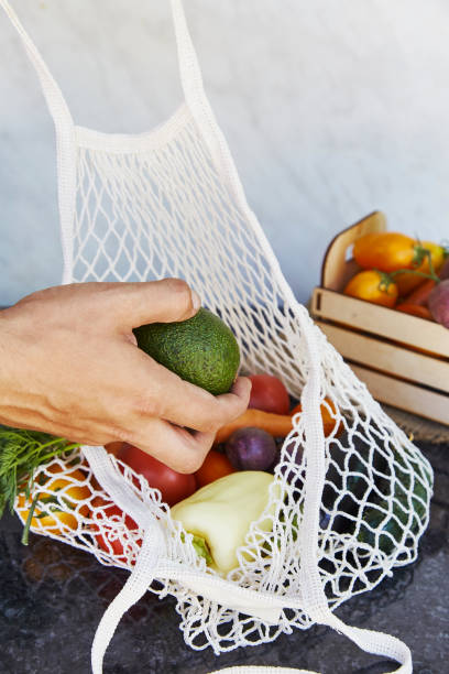 istock Man puts avocado to the eco string bag with fresh vegetables - tomatoes, purple potatoes, eggplants, carrots, sweet pepper. Ecological concern, eco shopping. Vegan eco-friendly lifestyle 1434940496