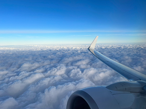 View from the airplane window. Beautiful cloudscape with blue sky. Wonderful panorama above white clouds as seen through window of an plane. Traveling by air concept