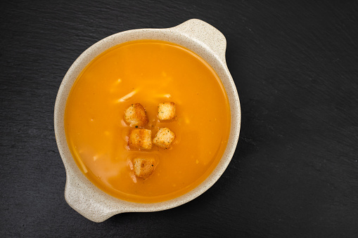 vegetable soup with crackers in white bowl on gray ceramic