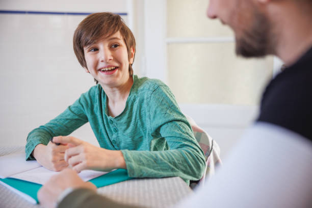 istock Happy boy looking at his father, doing homework at the table at home 1434943213