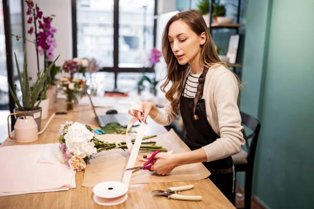 istock Young cheerful florist making bouquet at the counter 1434946434