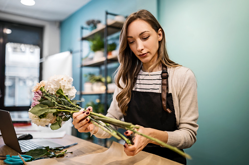 Cheerful young florist at the counter working at flower shop