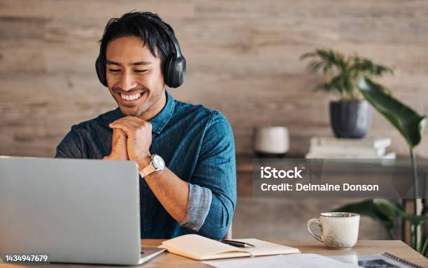 Remote Worker Laptop And Asian Man With Headphones Streaming Online Or Happy During Video Conference At Desk With Wifi Young Freelance Entrepreneur Working From Home Listening To Audio Music Stock Photo - Download Image Now