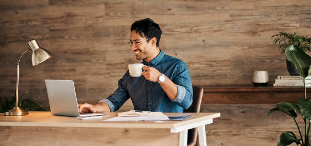 portátil, café y diseño con un hombre ejecutivo creativo en su oficina para gestionar una empresa online. computadora, correo electrónico y mecanografía con un joven diseñador masculino trabajando en un proyecto o informe en su escritorio - finance reading and writing learning business fotografías e imágenes de stock