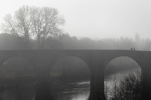 An old brick bridge over the river surrounded with fog