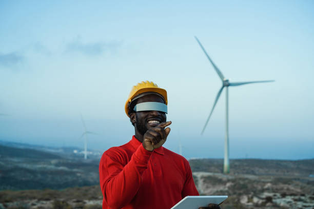 African engineer man using futuristic augmented reality glasses on a windmill farm stock photo