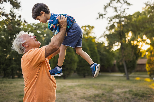 Grandfather holding his grandson in the air in a public park
