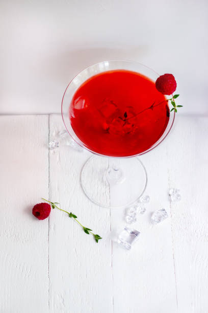istock Close-up of red alcohol cocktail with raspberry and thyme on white wood table. 1434952841