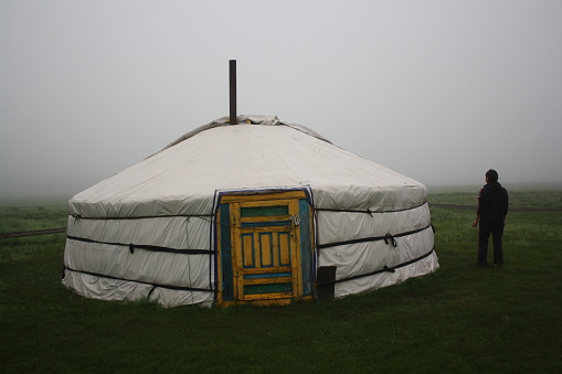 Nomadic tent (ger) and a woman in the mist of the tranquil meadow, Khuvsgul, Mongolia. The surrounding meadow is cold and quiet. Some nomadic families live around the area.