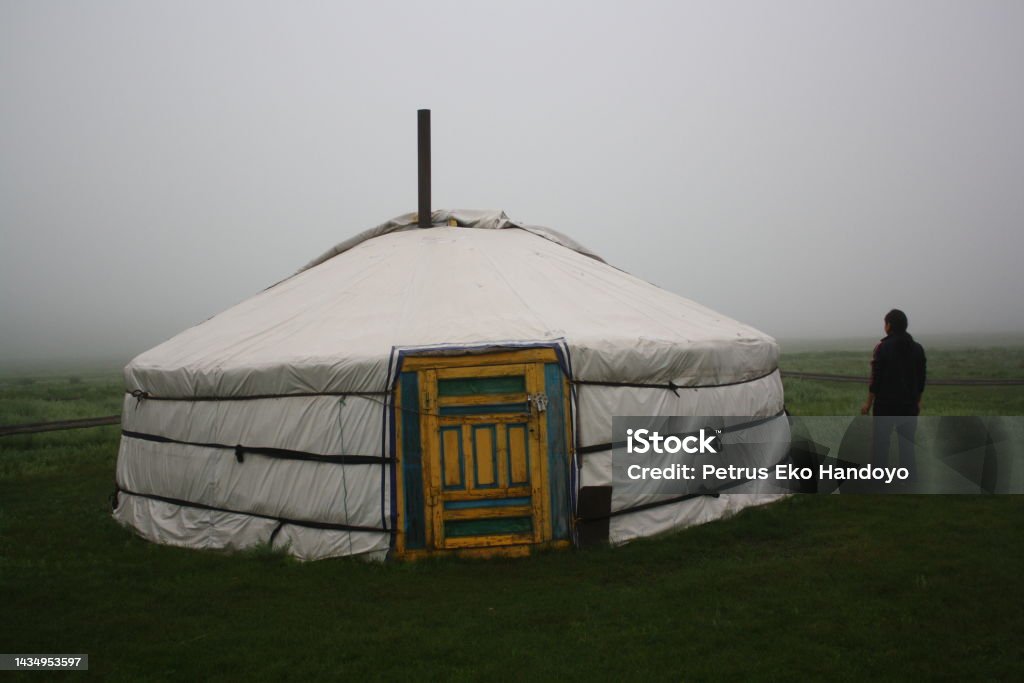 Nomadic tent and a woman in the mist of the tranquil meadow, Khuvsgul, Mongolia. Nomadic tent (ger) and a woman in the mist of the tranquil meadow, Khuvsgul, Mongolia. The surrounding meadow is cold and quiet. Some nomadic families live around the area. 35-39 Years Stock Photo