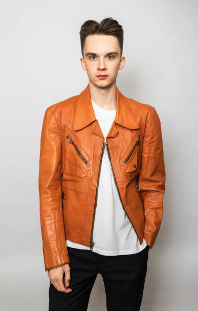 Confident young man wearing vintage leather jacket studio shot on gray background stock photo