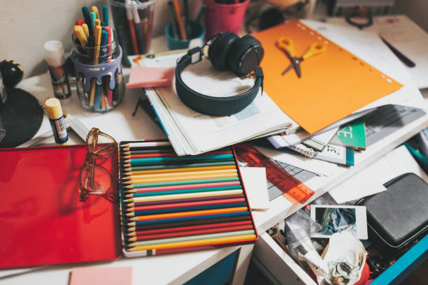 high angle view on school child´s untidy desk at home with workbooks, pens and school material spread over