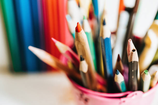 close up of various wooden colored pencils on beaker on desk