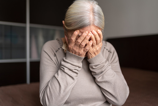 Anciana solitaria deprimida se cubrió la cara con ambas manos photo