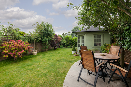 Newmarket, Suffolk, England - May 30 2018: Traditional house landscaped garden with shed, patio table, chairs and lawn