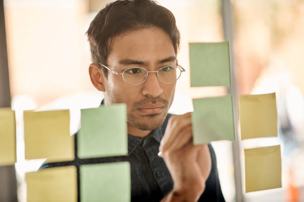 Man writing, sticky note in office and planning corporate strategy schedule for creative design organization work. A modern businessman, company working calendar and professional employee brainstorm hombre escribiendo, nota adhesiva en la oficina y planificación del cronograma de estrategia corporativa para el trabajo de organización de diseño creativo. un hombre de negocios moderno, calendario de trabajo de la empresa y lluvia de ideas de empleado