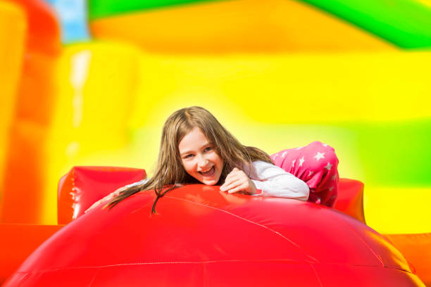 happy smiling girl auf inflate yellow castle - house bouncing multi colored outdoors stock-fotos und bilder