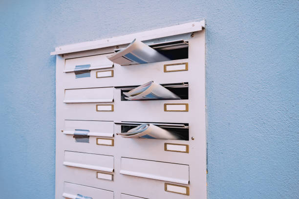 la boîte aux lettres d’un immeuble résidentiel avec des journaux quotidiens qui se démarquent avec des publicités et des nouvelles. - box package delivering mail photos et images de collection