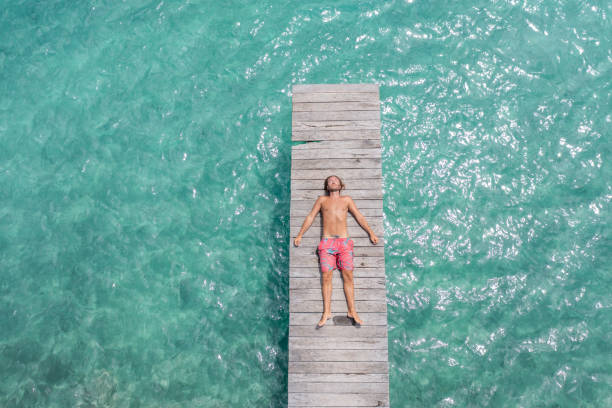 Drone view of woman relaxing on pier above lagoon 30's woman relaxes in nature on the beautiful lake of Bacalar, Mexico man sleeping top view stock pictures, royalty-free photos & images
