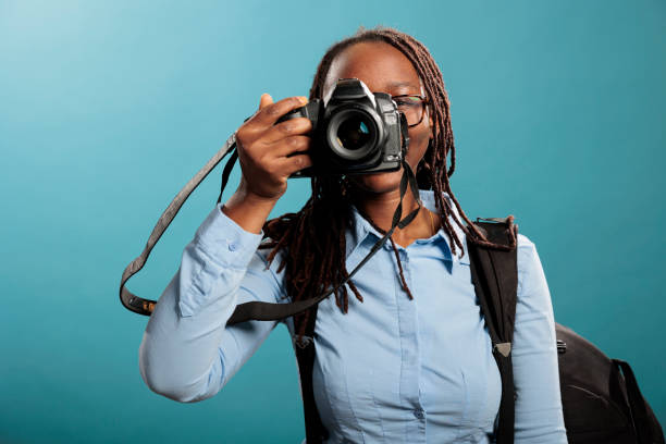 istock Professional photographer with photographing modern device taking pictures while looking at camera on blue background. 1434970486