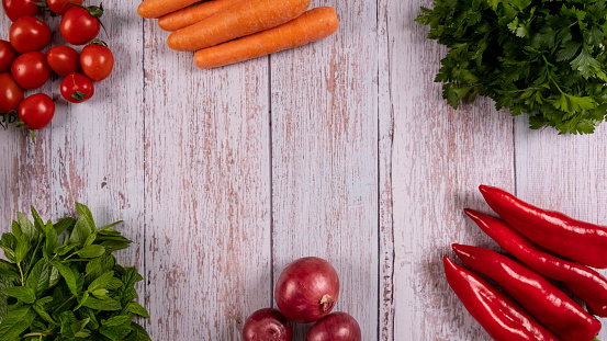 Blank image of organic and fresh vegetables of cherry tomatoes, parsley, mint, carrot, green onion, paprika and onions in wicker basket on wooden old background