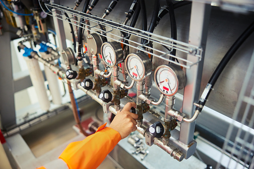 Close-up of a male engineer adjusting gauges while working in a power station producing heat for homes using water