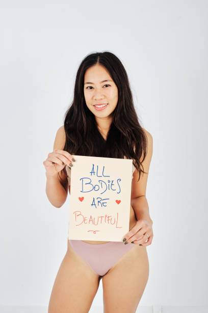 asian woman smiling and showing body positivity placard - panties underwear transparent women imagens e fotografias de stock