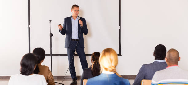 istock Confident man with microphone speaking at corporate business event 1434977123