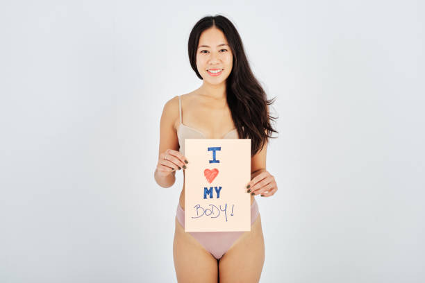 happy asian woman with handwritten body positivity poster - panties underwear transparent women imagens e fotografias de stock