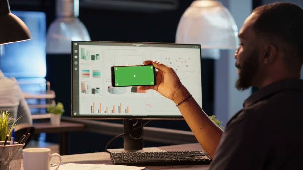 istock Office worker holding smartphone with horizontal greenscreen 1434979510